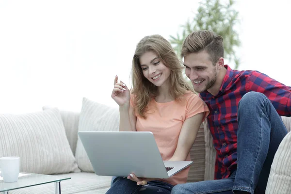 リビング ルームに座っているノート パソコンでテレビ番組を見て彼のガール フレンドを持つ若者 — ストック写真