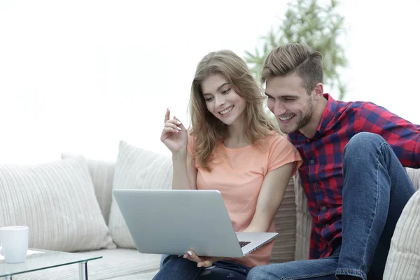 Joven con su novia viendo un programa de televisión en el portátil sentado en la sala de estar — Foto de Stock