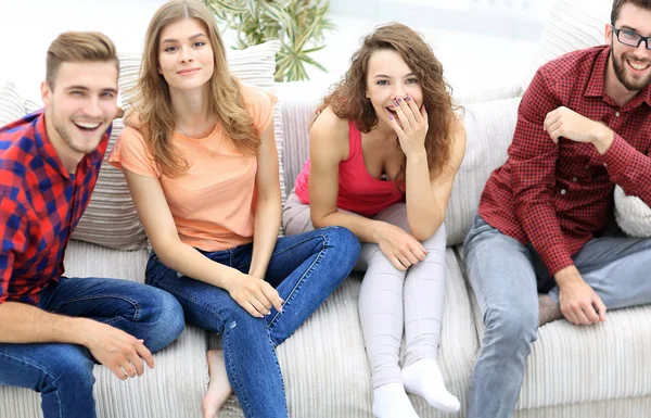 Grupo de amigos alegres viendo videos, sentados en el sofá —  Fotos de Stock