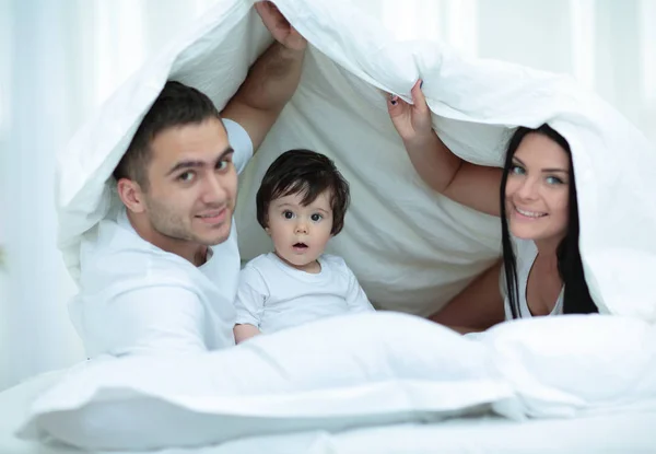 Familias con niños en la cama bajo una manta —  Fotos de Stock