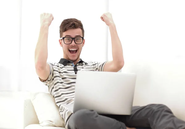 Hombre feliz con el ordenador portátil sentado en el sofá — Foto de Stock