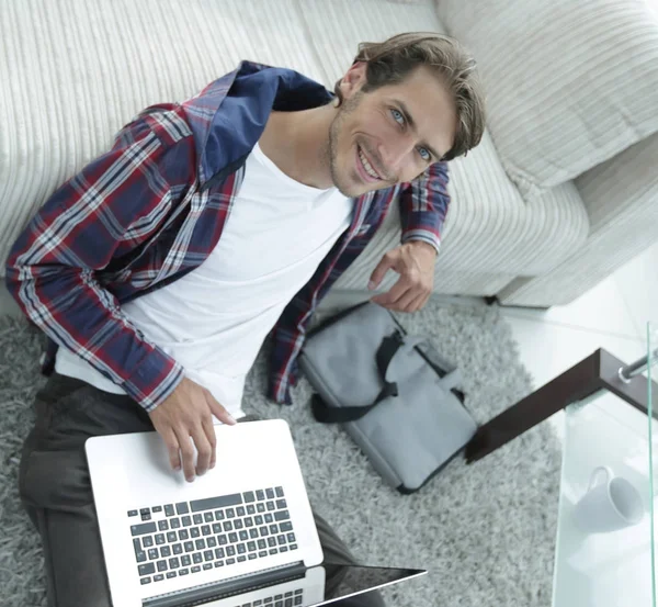 Business guy with laptop sitting on carpet in living room. — Stock Photo, Image