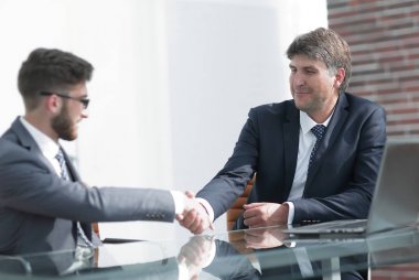 Toplantı sırasında iki iş arkadaşı el sıkışıyor.