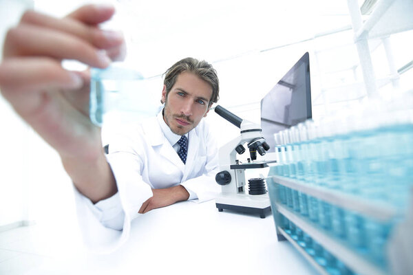 Portrait of a chemist holding a tube with liquid.