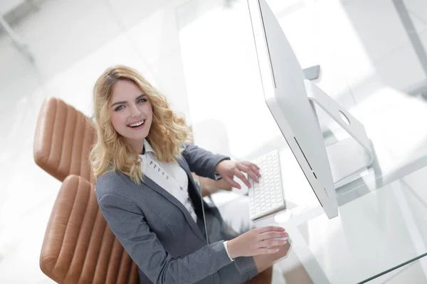 Glimlachende zakenvrouw zitten achter een bureau — Stockfoto