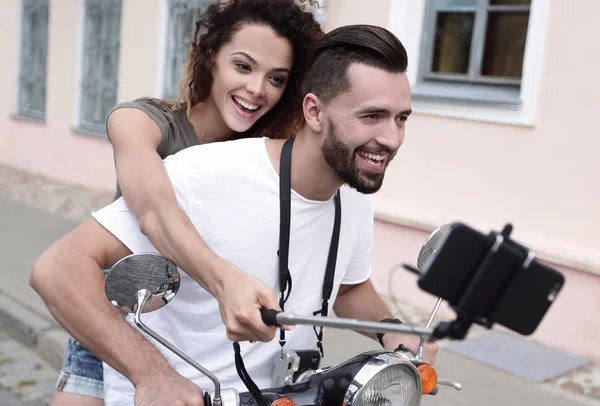 Pareja feliz en scooter haciendo selfie en el teléfono inteligente al aire libre — Foto de Stock