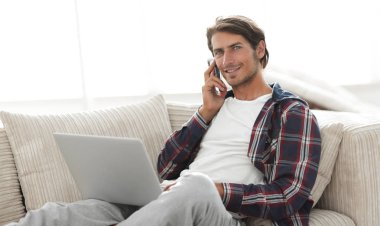 cep telefonu üzerinde konuşurken laptop ile ciddi genç adam