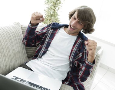 dizüstü bilgisayar ekranına bakarak mutlu genç adam