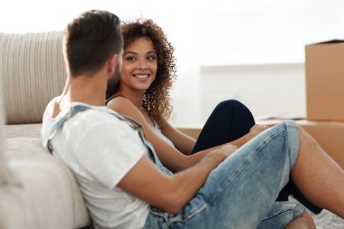 Yeni evliler yeni bir dairede kanepede oturuyor..