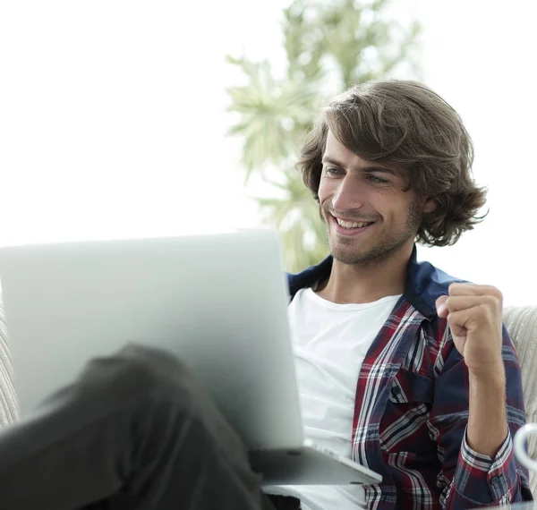 Cara muito feliz com um laptop sentado perto de uma mesa de café . — Fotografia de Stock