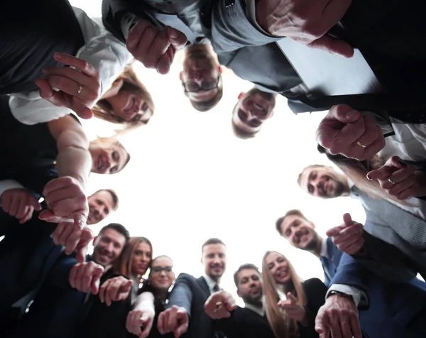 business team is forming a circle and pointing at the camera .
