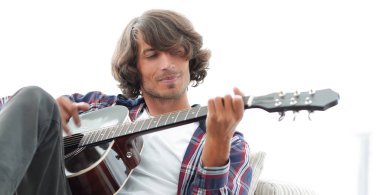 Yakışıklı adam evde kanepede gitar çalmaya