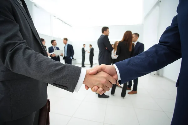 Nahaufnahme des Handschlags von Geschäftspartnern vor dem Hintergrund des Geschäftsteams — Stockfoto