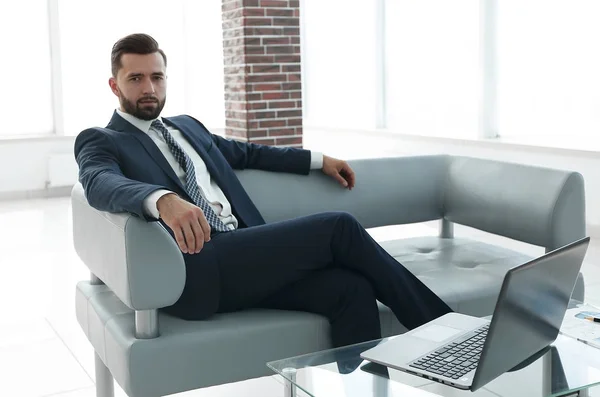 Empresário sentado no lobby de um escritório moderno . — Fotografia de Stock