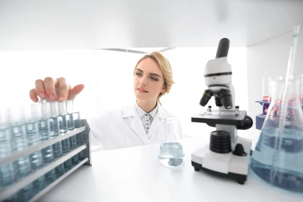 Mujer joven analizando muestras en un laboratorio — Foto de Stock