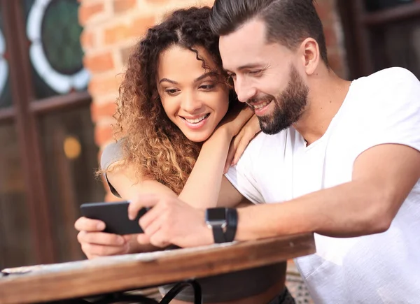 Feliz pareja amorosa usando un teléfono inteligente sentado en la terraza — Foto de Stock
