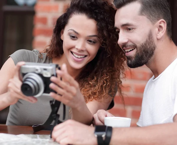 Retrato de um casal sentado em um café e olhando fotos — Fotografia de Stock