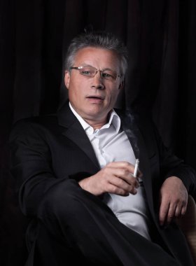 bir sandalyede oturan bir sigara ile üst düzey iş adamı