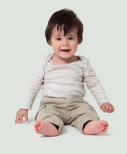 Αστείο μωρό κάθεται στο πάτωμα, απομονωμένη πάνω από λευκό — Φωτογραφία Αρχείου