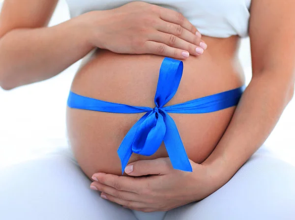 Close-up van een zwangere vrouw koppelverkoop een blauw lint op haar buik — Stockfoto