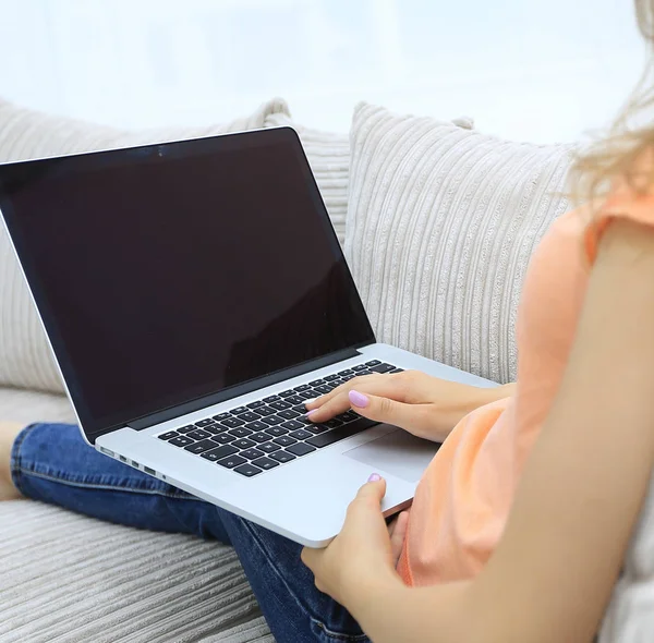 Giovane donna che lavora con il computer portatile seduta sul divano — Foto Stock