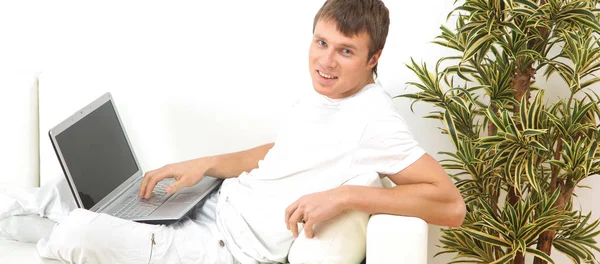 Jovem muito focado usando laptop enquanto sentado confortavelmente . — Fotografia de Stock