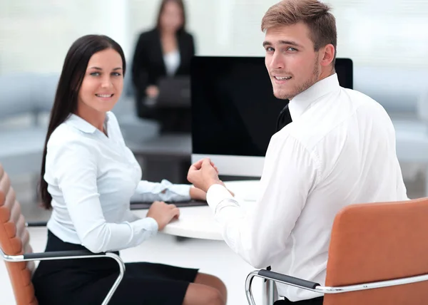 Mitglieder des Geschäftsteams sitzen am Schreibtisch und schauen in die Kamera . — Stockfoto