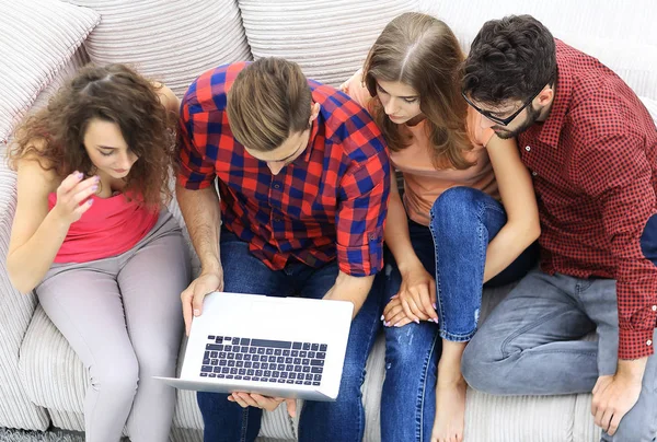 Grupo de amigos com laptop sentado no sofá . — Fotografia de Stock