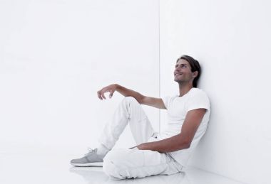 Beyaz bir duvar oturan rüya gibi genç adam.