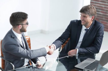 İş adamları el sıkışır, masada otururlar. .