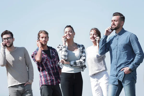 Grupo de estudiantes hablando en sus teléfonos inteligentes . — Foto de Stock