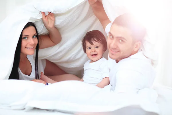 Atractiva familia joven en el dormitorio — Foto de Stock