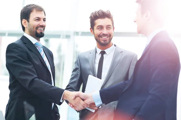 在一个现代化的办公室里，成熟的商人与他的伴侣和同事握手，与他们签订协议 — 图库照片