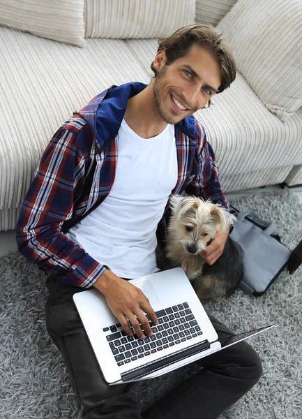 Knappe jongen met laptop knuffelen zijn hond en zitten in de buurt van de Bank — Stockfoto