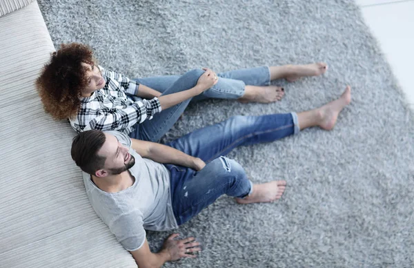Pareja recién casada sentada en una alfombra en una nueva sala de estar — Foto de Stock