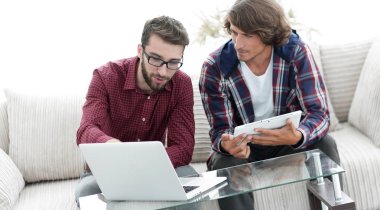 dizüstü ve tablet kanepede oturan çalışan iki genç adam