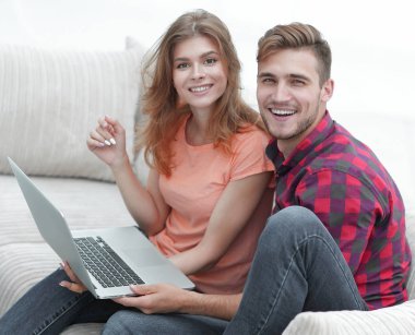 Dizüstü bilgisayarı olan iki öğrenci kanepede oturuyor.