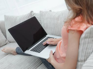 koltukta oturan dizüstü bilgisayar ile çalışan genç kadın