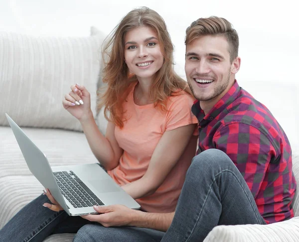 Dizüstü bilgisayarı olan iki öğrenci kanepede oturuyor.