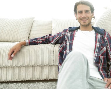 Kendine güvenen adam rahat bir oturma odasında halı üzerinde oturan.