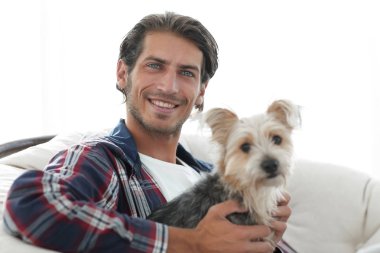 gülümseyen bir adam büyük bir koltukta otururken köpeğini okşayarak Close-Up.