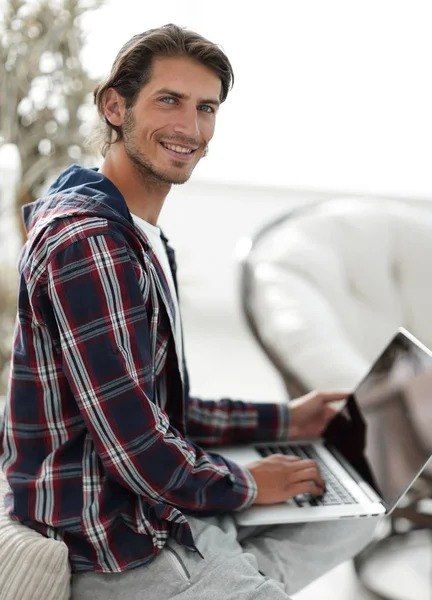 Stylowe młody człowiek pracuje na laptopie i patrząc na kamery — Zdjęcie stockowe