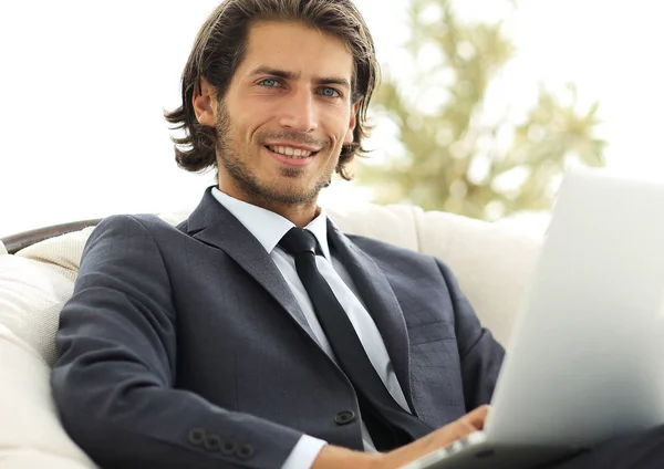 Homem de negócios com um laptop sentado em um chai elegante confortável — Fotografia de Stock