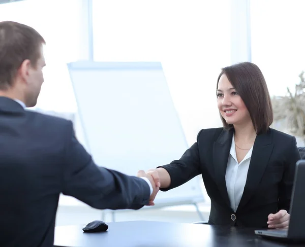 Affärskvinna som skakar hand med en affärspartner över ett skrivbord — Stockfoto