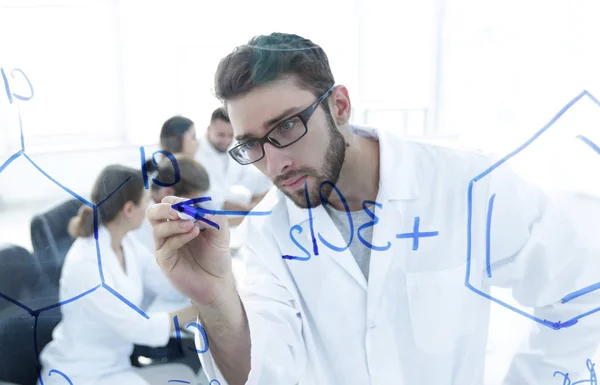 Van achter schrijft de glass.scientist een markering op een glas Board. — Stockfoto