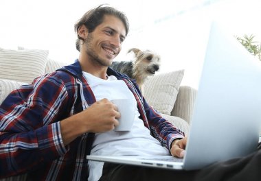 genç adam kanepede yakın katta oturan çay içiyor.