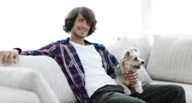 şık adam köpeğiyle kanepede oturan.