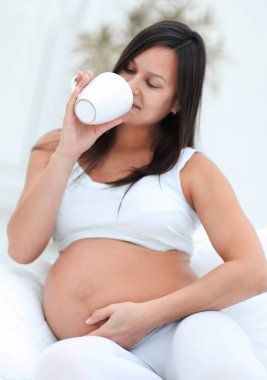 oturma odasında süt içme mutlu hamile kadın.