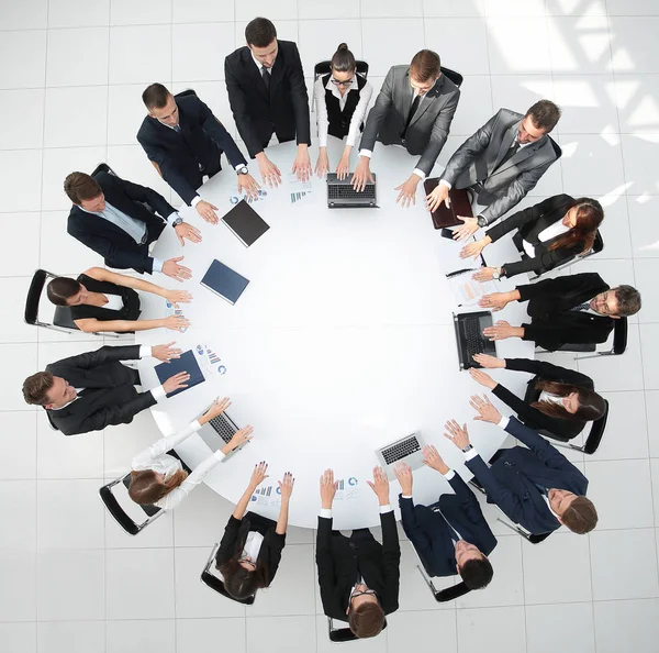 Groep zakenmensen zit aan de ronde tafel, en zet zijn handpalmen op de tafel — Stockfoto