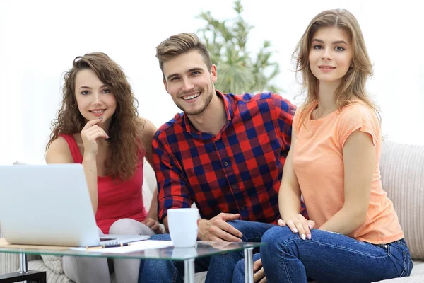 Group of students sitting on a couch behind a coffee table. — Stock Photo, Image